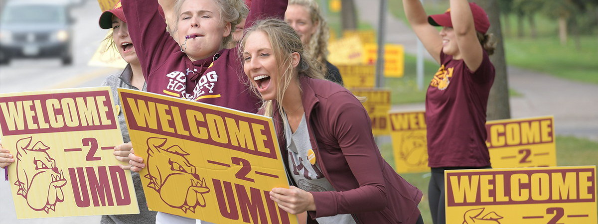 Students cheer and hold signs reading "Welcome 2 UMD".